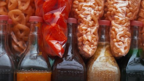 4k Up-close view of Mexican fried snacks and colorful slush syrup bottles