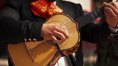 4k Up-close view of a five strings instrument called vihuela being played by a mariachi