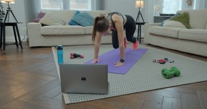 Sportswoman doing morning fitness exercises with help of her instructor online on laptop. Healthy lifestyle. stretching, leaning forward. Training on distance.