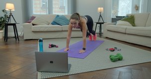 Sportswoman doing morning fitness exercises with help of her instructor online on laptop. Healthy lifestyle. stretching, leaning forward. Training on distance.