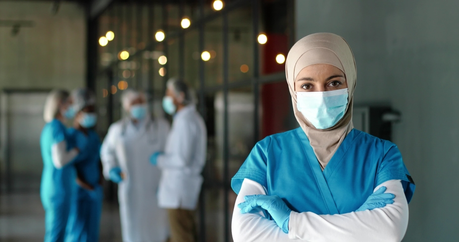 Portrait of Arab woman doctor in hijab, medical mask and gloves standing in hospital. Muslim female medic in traditional headscarf in clinic. Covid-19. Arabian nurse. Coronavirus. Protected. | Shutterstock HD Video #1060332050