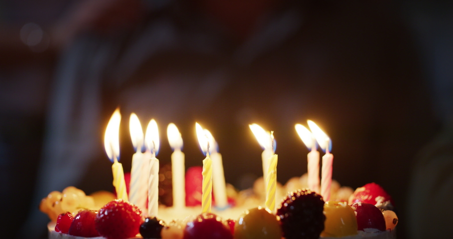 Close up macro shot of candles of birthday cake being blowed by birthday person after dream expression. Concept of family, friendship, holidays,celebration, present | Shutterstock HD Video #1060334234