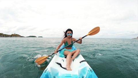 Young pretty woman in sunglasses rowing in a kayak