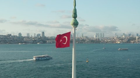 Vibrant Red Turkish Flag waving in wind on top of Circling Maiden's Tower in Water in Istanbul, Aerial circling shot