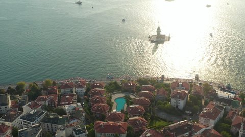 Hotel Resort on Bosphorus Riverside with view on Maiden's Tower in beautiful Afternoon light, Slow forward Aerial tilt down