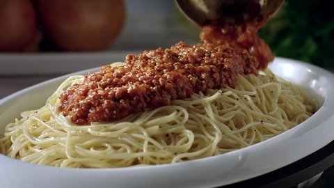 Bolognese with minced meat and tomato sauce is poured over spaghetti pasta.
