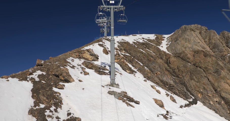 Using ski lift in the Alps, lack of snow on the top of the mountain after wind blowing it away Royalty-Free Stock Footage #1060345529