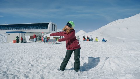 Funny cute adorable young woman does joking floss dance from viral internet meme video. Winter holiday mood, vacation destination, top of mountain near ski lift. Social media influencer concept