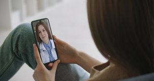 Woman using medical app on smartphone consulting with doctor via video conference. Female using online chat to talk with family therapist and checks possible symptoms during pandemic of coronavirus.