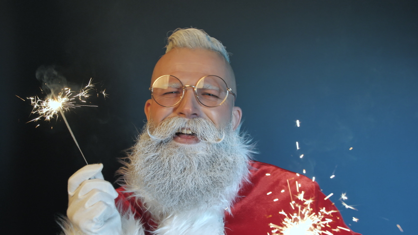 Happy Funny Emotional Santa Claus Sings Song Enjoying Music, Dances Playing with Magical Sparklers, Looking at Camera Closeup Indoors. Positive Festive Mood at New Year, Christmas Holidays Celebration Royalty-Free Stock Footage #1060350407