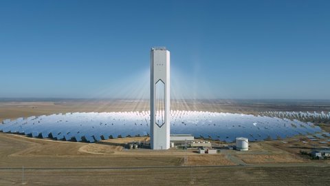 Aerial footage of a сoncentrated solar power station with a hollow tower. Modern or futuristic power plant. Solar farm center. Renewable energy concept.