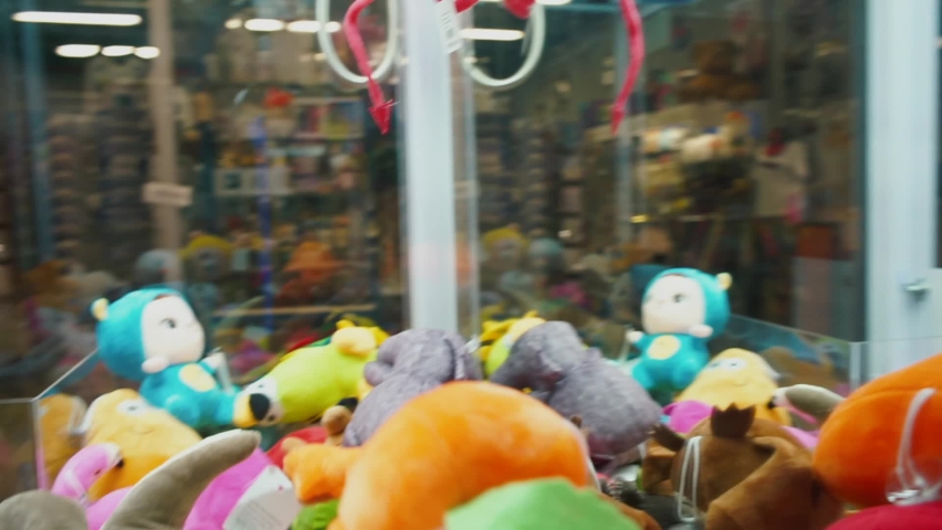 Claw machines are favorite gambling  game for many kids filled with toys. Machine changes strength of grip depending on whether game is supposed to result in win or not. Triggers for pleasure center Royalty-Free Stock Footage #1060351355
