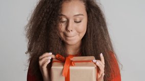 Beautiful excited brunette girl get gift on her birthday happily looking in camera isolated on white background