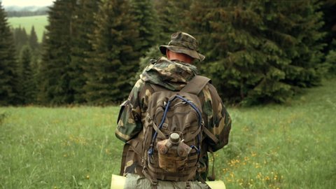 View from rear, man walking wearing military disguise camouflage uniform hunting. Hunting, angling concept. Environment concept.