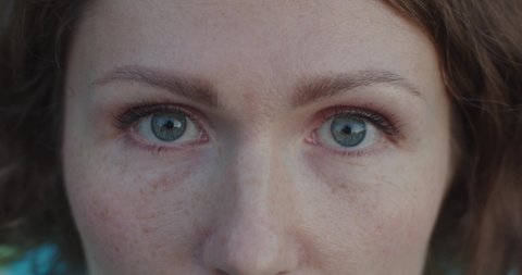 Extra close up female blue eyes with little make-up mascara opening slow motion detailed crop. Macro portrait of white woman with freckles looking seriously. Skin care healthy eyes eyesight concept