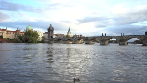 
shot in motion of Charles Bridge and flowing Vltava river in the center of the capital city of Prague at sunset in the Czech Republic