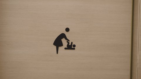 Close up of baby rest room sign on the doors. Person entering into baby changing room.