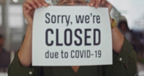 Woman closing business due to covid-19 pandemic outbreak with sign