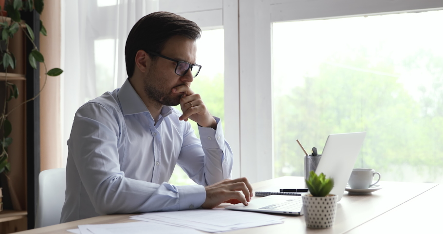 Side view serious young businessman in eyewear and formal shirt working on computer at home office, stuck with difficult task, web surfing problem solution or making marketing research, casual workday Royalty-Free Stock Footage #1060360709