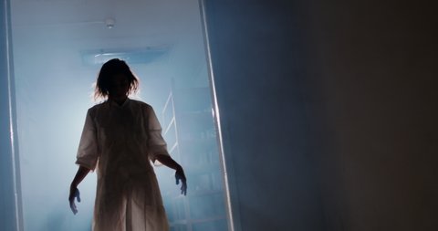 Scary girl in white straitjacket agonizing in exorcism. Creepy patient escaping from nuthouse - halloween, horror movie 4k footage