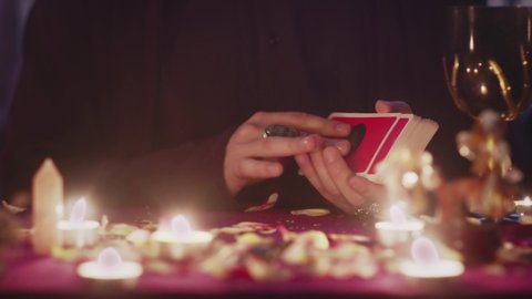 Male fortune teller puts occult tarot cards on the table. Magical pagan destiny reading ritual.