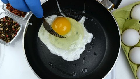 Pouring chicken egg into hot pan and cooking fried eggs. Scrambled eggs cooking. Simple tasty homemade food preparation concept. Close-up.