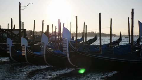 Empty gondola boats swaying on the water during the sunrise in Venice Italy