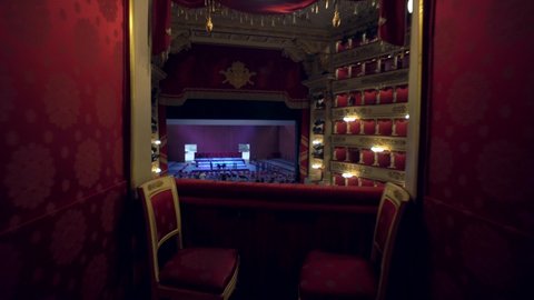 Milan, Italy, 12.10.2020: Teatro alla Scala. A view inside the building of an empty concert hall made of red velvet and an empty stage. Opera theatre. The workers set up a stage for the performances.