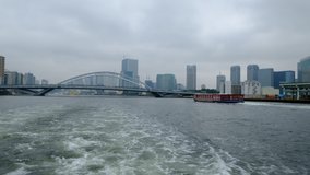A back view of a boat ride, a bridge, another ferry and cityscape of Tokyo are visible, 4K video, Japan.