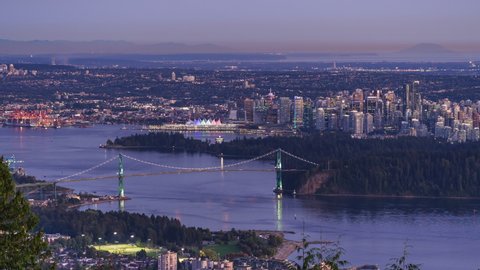 Zoom out timelapse view of Vancouver cityscape showing Lions Gate Bridge and Downtown buildings at dusk in Vancouver, British Columbia, Canada.