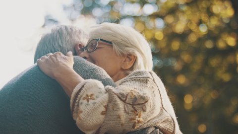 Elderly couple in love embracing in the park on an autumn day. High quality 4k footage