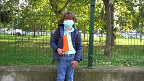 Boy child 6 years old with mask and backpack go to school during Covid-19 Coronavirus outbreak - school open until the next lockdown