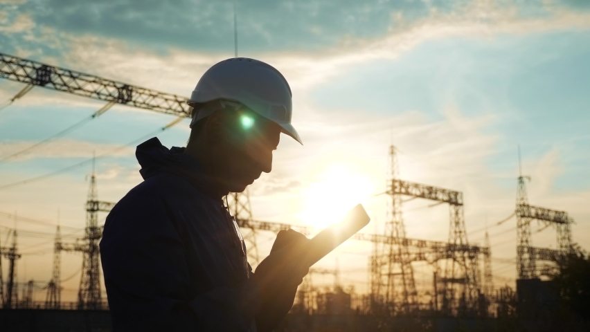 electrical silhouette worker engineer a working with digital tablet, near tower with electricity. energy business technology industry concept. electrical power studying reading documents on tablet Royalty-Free Stock Footage #1060394177