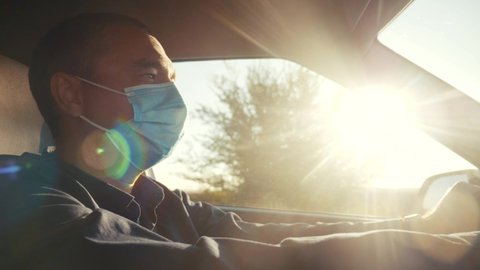 worker driver wearing a medical mask drives a car during the coronavirus period. delivery during the pandemic covid 19 parcel concept. man wearing a mask taxi driver protection against coronavirus