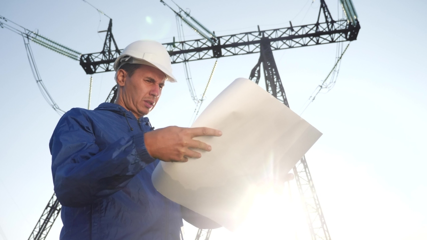 electrical engineer worker in helmet a working with documents, near tower with electricity. business energy technology industry power concept. electrical engineer studying reading documents Royalty-Free Stock Footage #1060394204