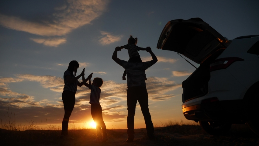 Happy family children kid together standing next to car watching the sunset silhouette in park. family travel dream journey concept. happy family stand with sunlight their backs watching in the park | Shutterstock HD Video #1060394231