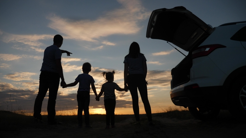 Happy family children kid together standing next to the car watching the sunset silhouette in the park. family travel dream concept. happy family stand with their backs watching in the park sunlight | Shutterstock HD Video #1060394237