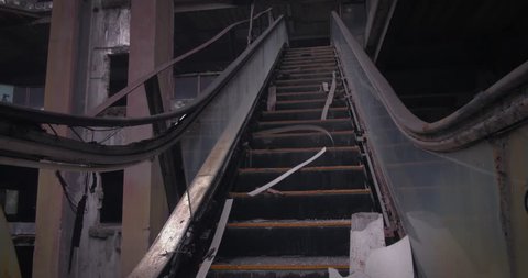Broken facilities of former shopping mall. Destroyed escalator in empty creepy building 