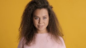 Beautiful delighted brunette girl with curly hair flirty showing wow expression isolated on yellow background