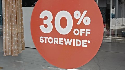 Red round sign hanging on a glass window with the inscription 30% off