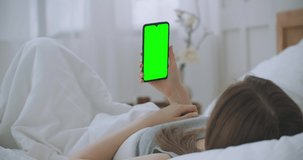Beautiful woman using smartphone, touchscreen display in light room. Young attractive brunette woman a speak through video call on smartphone webcam with friend at bedroom in the morning