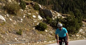 Male road cyclist climbing a mountain pass pedaling hard. Effort, motivation, cycling training