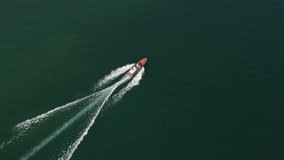 Vintage wooden boat in sea. Modern wooden boat In motion on the water top view. People in boat aerial view Boat drone video. 