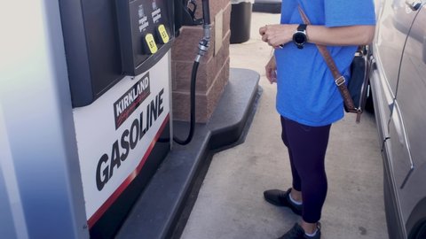 Frederick, MD USA 10/08/2020: A caucasian woman is pumping gasoline into her car at a self service gas pump at Costco Wholesale. Costco offers discounted gas prices to its members