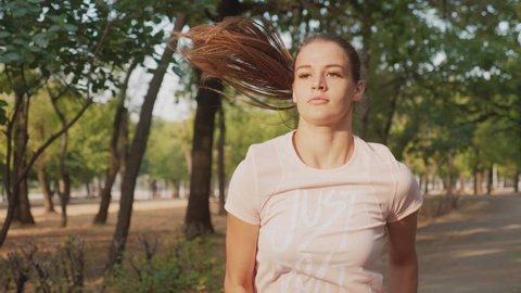 Young woman runner training in summer park. Close up fitness woman jogging outdoor. Tired girl jogger breathing after run marathon in park. Morning running concept
