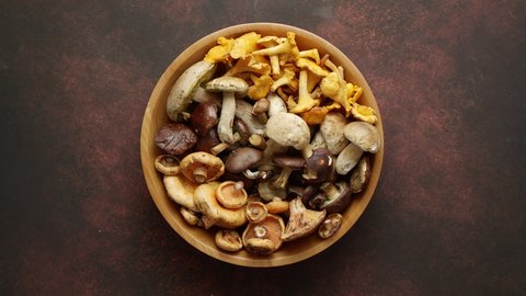 Raw and fresh forest various mushrooms in bowl standing on rusty table. Organic vegetarian healthy food. Top view, flat lay.