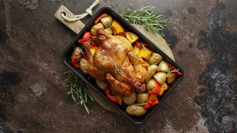 Delicious whole chicken cooked with pumpkin, pepper and potatoes. Served in metal baking pan. Decorated with rosemary. Autumn food concep. Top view. Flat lay.