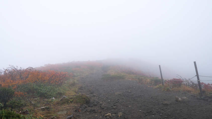 Walk the summit from a first-person view. Mountain fog in strong winds. Early morning hike on a cloudy day