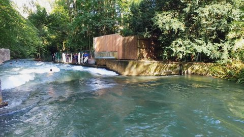 Munich, Germany - circa August, 2018: Surfers having fun on the Isar in Englisher garden in summer