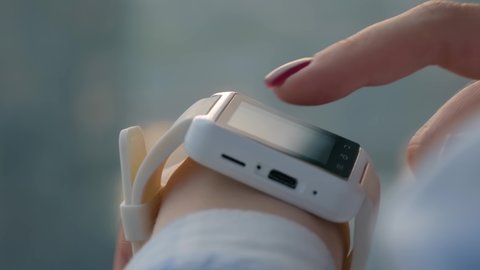 Woman using wearable white smartwatch device in office or home - scrolling and touching - close up side view. Relax, leisure time, entertainment and technology concept